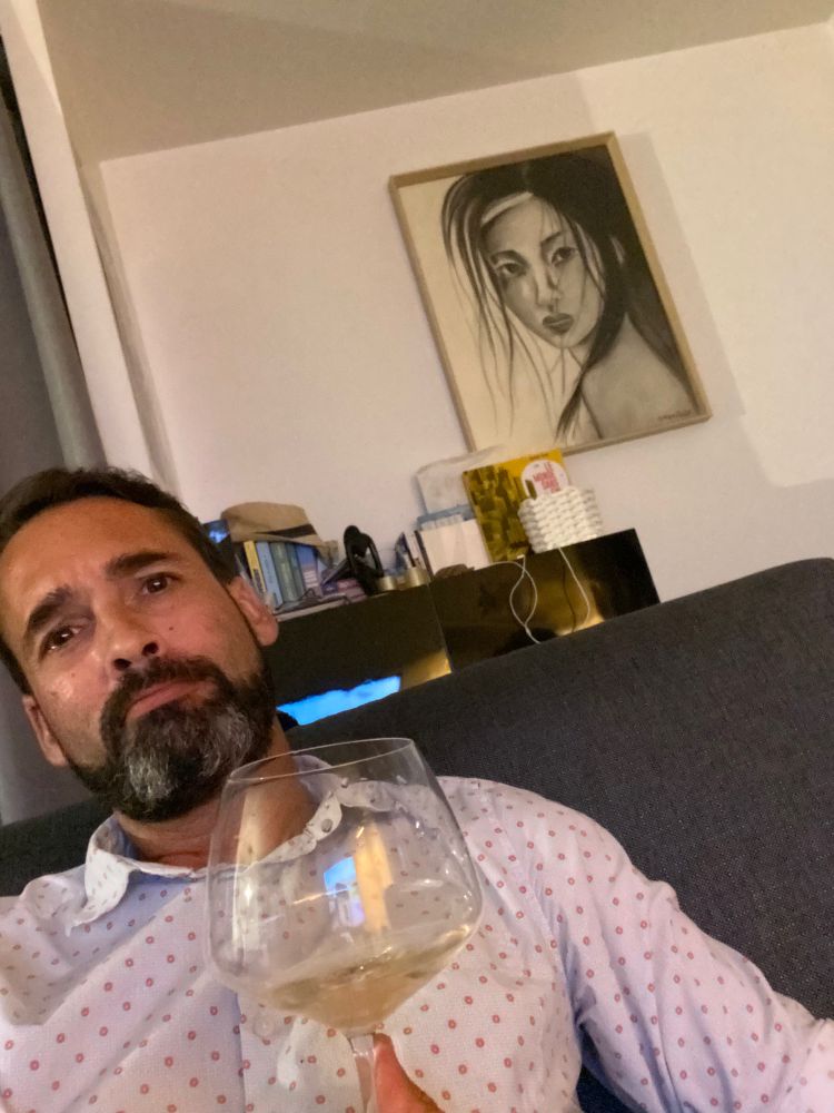 Homme buvant une rosé de Provence Domaine de Barrieras, devant un tableau de sa mère. Il se demande de qu’il va manger tout en caressant son chat Losa.