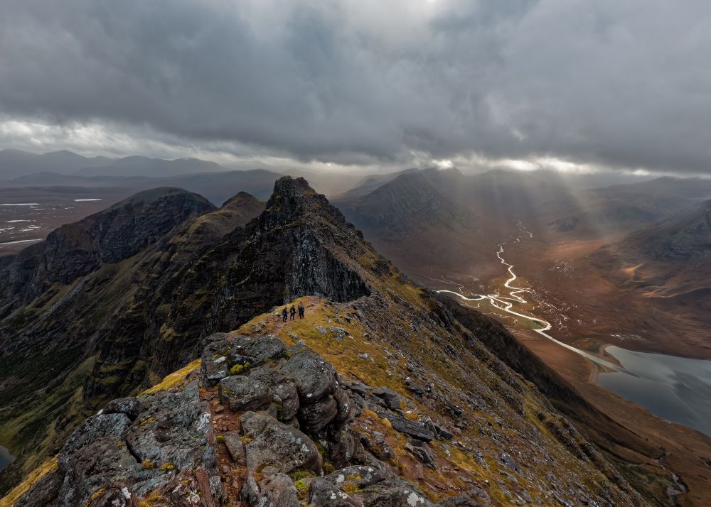 Hikers cross the ridge on the summit of An Teallach under threatening skies