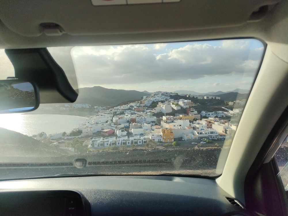 Landschaft mit Meer und einem Dorf am Berg, durch  Autoscheibe