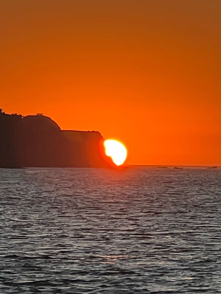 Sun setting over the ocean with an orange sky