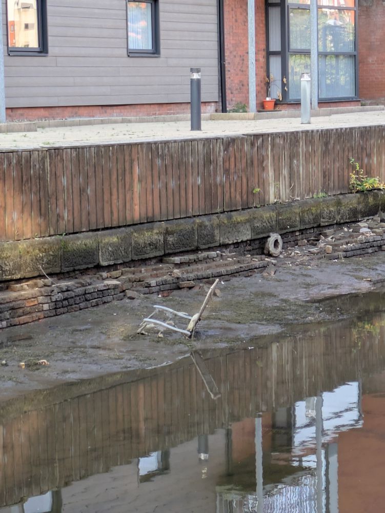 A reclining garden chair stuck in the mud in a partially drained Manchester canal