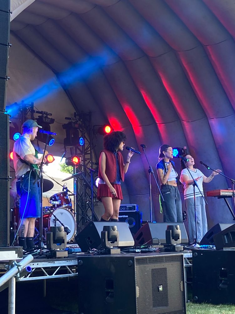 Becky centre stage accompanied by singers and drums and guitar 