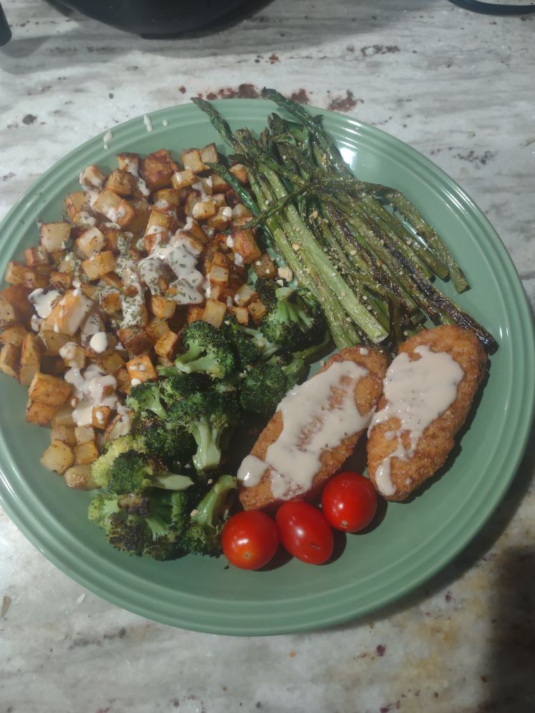 Roasted potatoes with tahini miso sauce, roasted asparagus and broccoli and a couple simulate chicken tenders and some cherry tomatoes 
