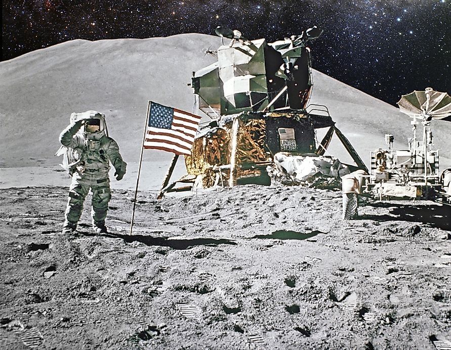 The Apollo 11 Lunar Lander, with either Buzz Aldrin or Neil Armstrong standing to the left of it next to the US flag, saluting the camera (presumably operated by the other astronaut who landed on Luna during the historic mission), and the Lunar Rover to the right.