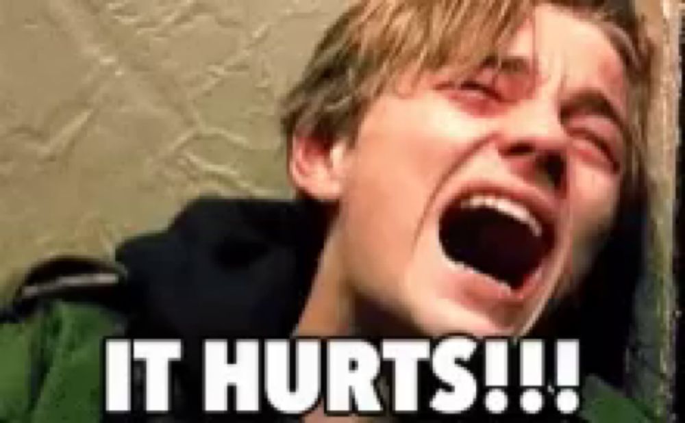 a young man is crying with his mouth open and the words `` it hurts !!! '' written on the bottom .