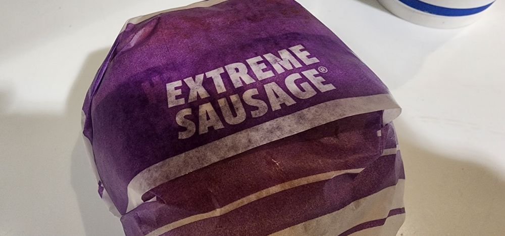 A wrapped breakfast sandwich with the words "EXTREME SAUSAGE" on the purple paper in white letters.