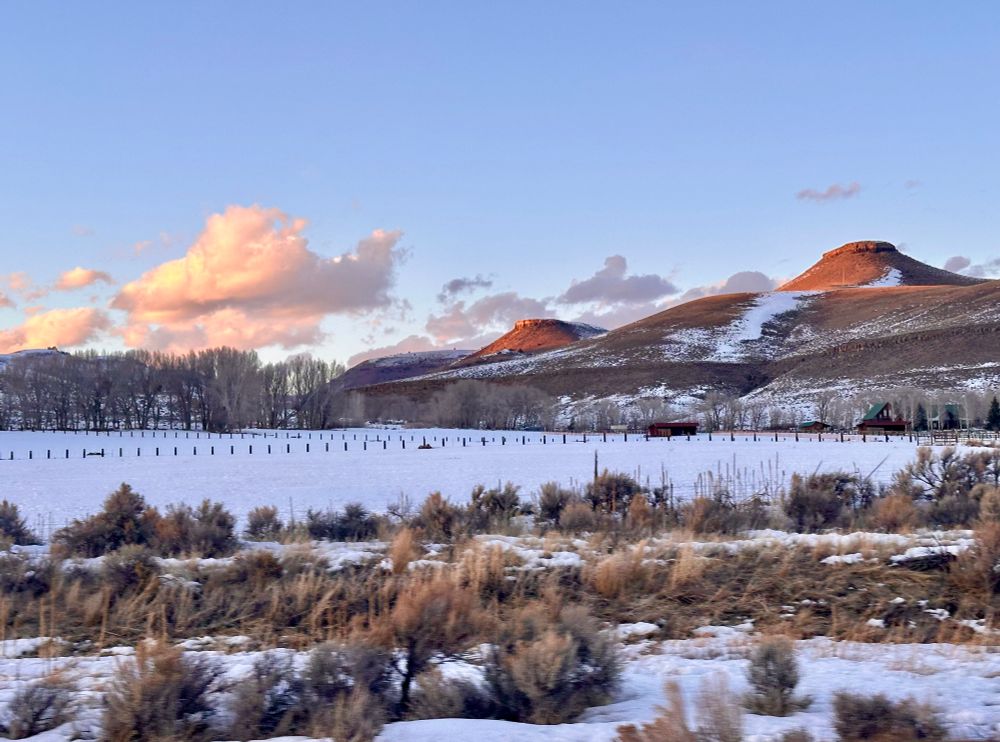 Snow-covered fields and peach-colored clouds at a ranch just west of Gunnison, CO.