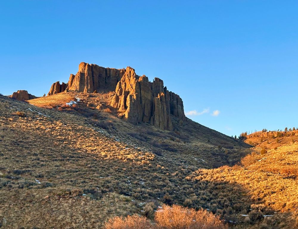 Eroded volcanic plug projecting above a steep, sage-covered hillside. Curecanti National Recreation Area north of Blue Mesa Reservoir, CO.