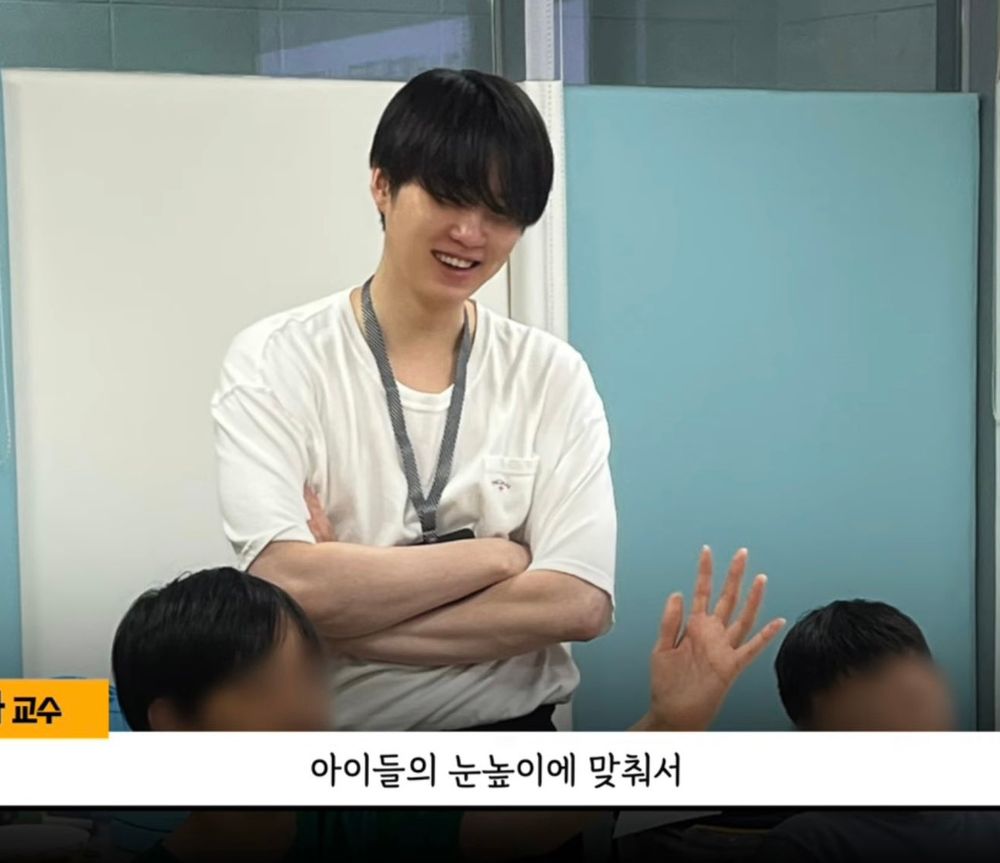 Suga of BTS wearing an id card on his neck, smiling with his teeth.