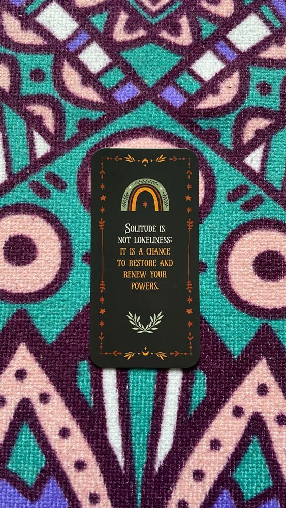 A black oracle card with a rainbow on it reads: solitude is not loneliness. It is a chance to restore and renew your powers. 