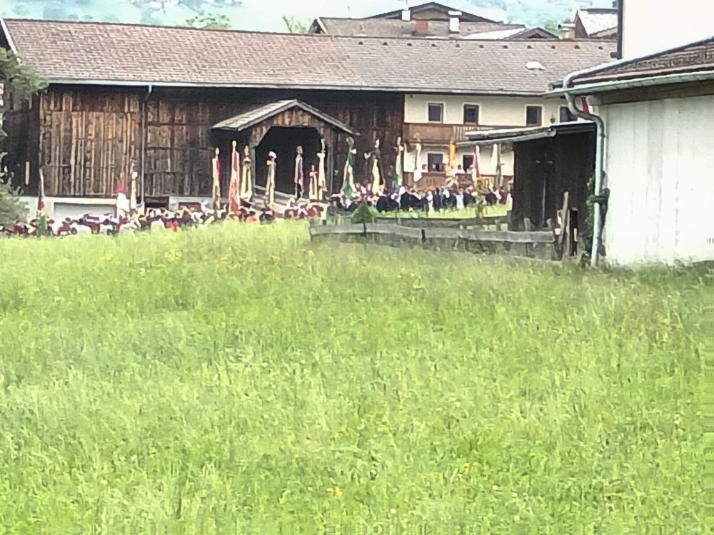 Feierliche Prozession mit vielen Fagnen zieht an einem Bauernhaus vorbei 