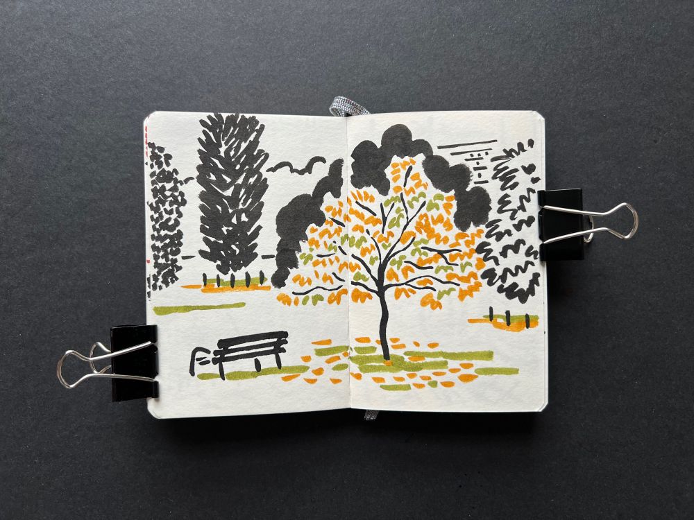 Sketchbook spread with brush pen ink illustration – a bench seen from the back with trees and green-ochre leaves fallen on the ground