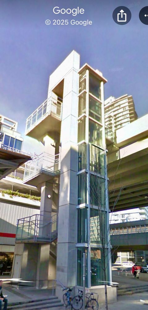 The pedestrian elevator and zigzagging outdoor staircase that climb the vertical distance between Pacific Blvd and Dunsmuir. (From Google Maps street view.)