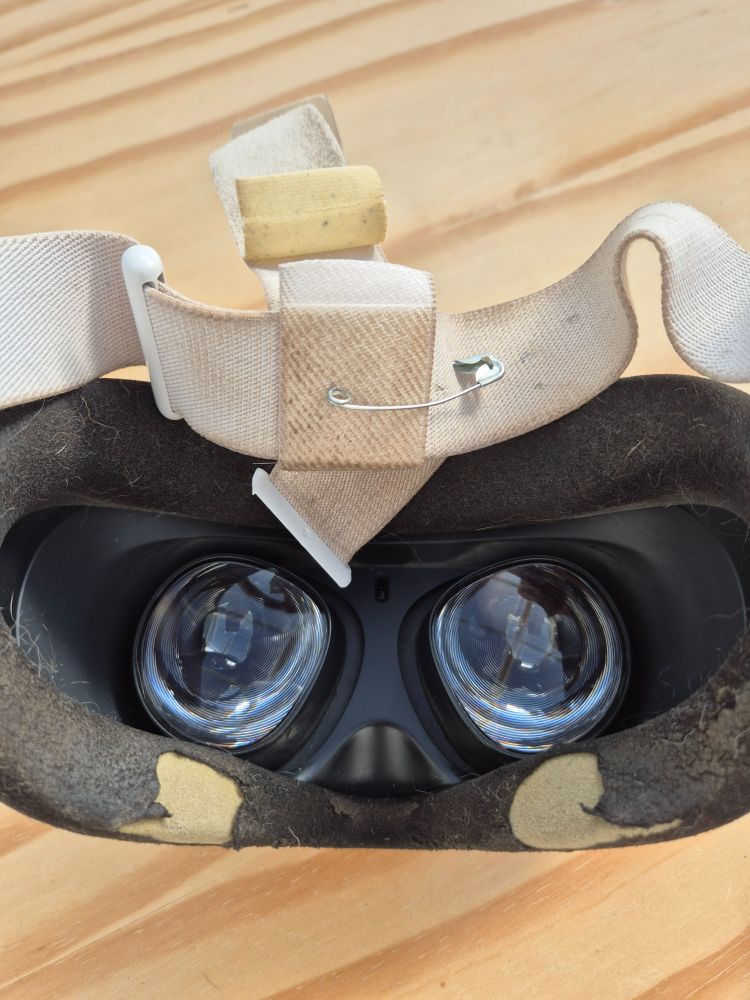 Quest 2 headset with damaged face cover and broken headstrap with a safety pin holding it together