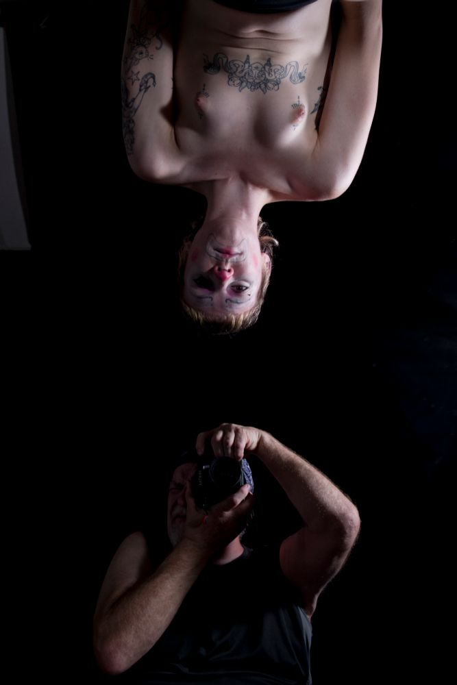 Aly is nude and upside down. I am clothed and right side up. A mirror is involved. I have a camera. Click click. 