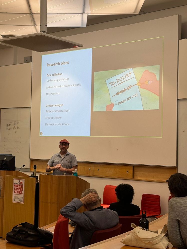 Carl presenting at a seminar. Screen behind him shows his research plans. There is a picture of SpongeBob's hands writing a to-do list. The list reads "Wake-up" which is crossed out, and "Finish my PhD".