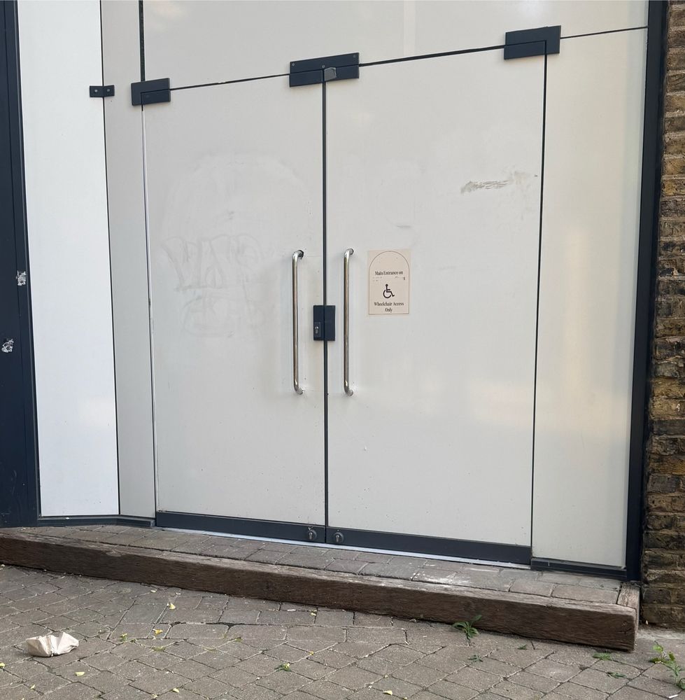 A set of white double fire doors. A small sign has the name of the restaurant, “Main entrance on [street round the corner]”, a disabled sign and “Wheelchair Access”

The doors open outwards onto a tiny, single step. 
