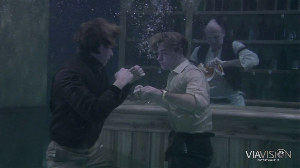 The under water bar fight scene from Top Secret. Two men square up, fists raised whilst a barman cleans glasses in the background. All whilst underwater 