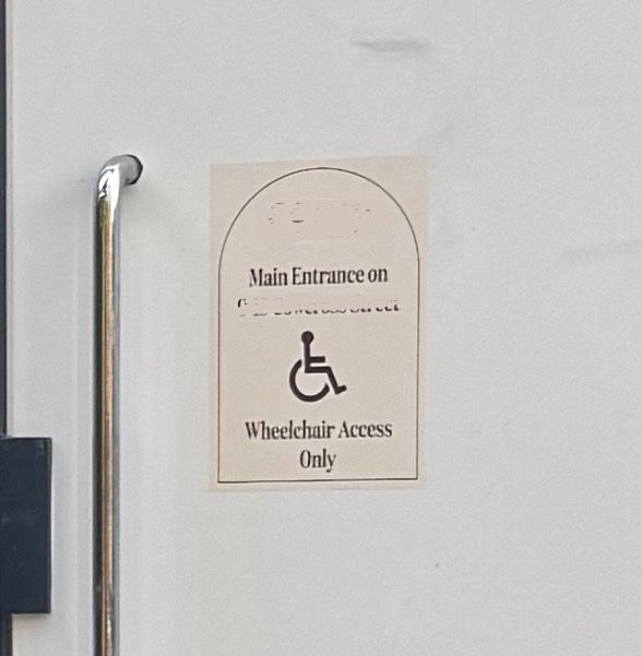 A zoomed version of the previous so people can read it more easily. As before: small sign has the name of the restaurant, “Main entrance on [street round the corner]”, a disabled sign and “Wheelchair Access”