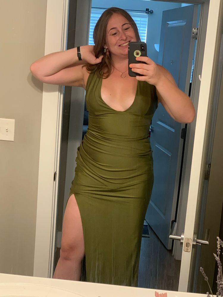 Nic takes a mirror selfie of herself in a scoop neck olive green dress