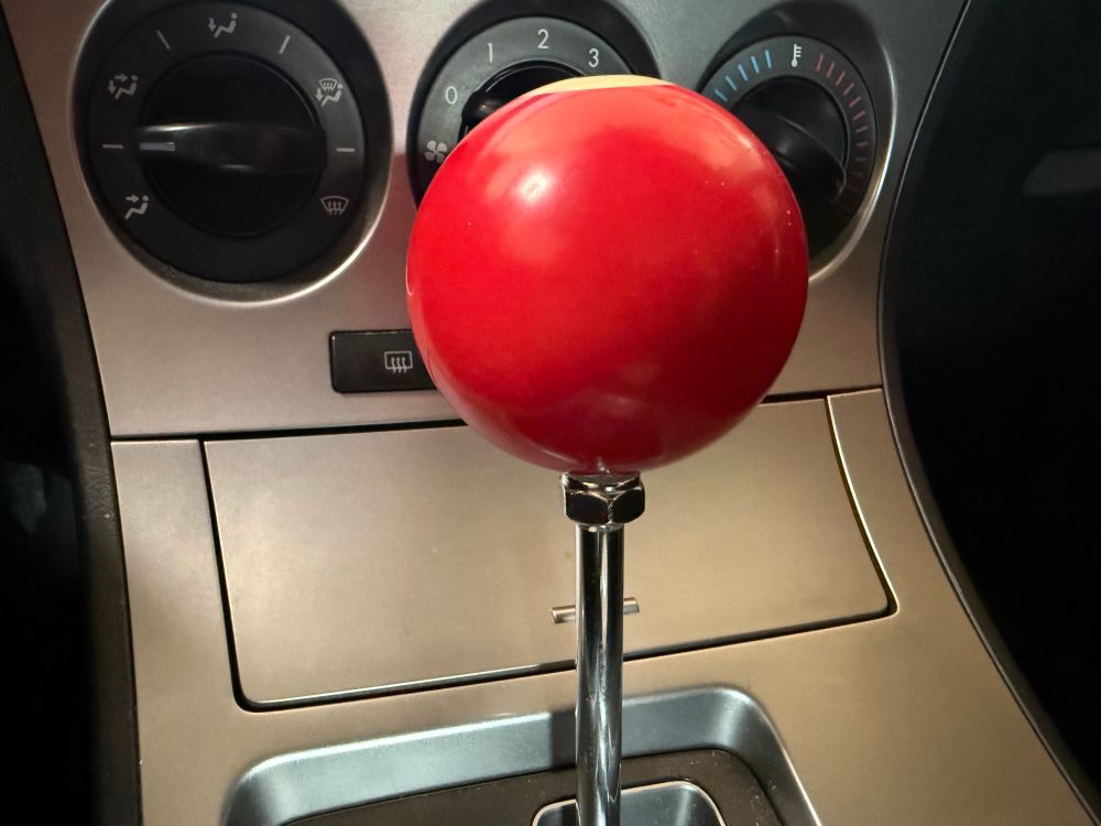 A low and front view of the 3 ball installation while gear is in park, showing the locking nut under the ball. The nut has a nylon gasket in it that bites the threads, so you put both on as low as thy will go, then work the nut back UP into the bottom of the ball (with a nylon washer in between as a cushion) which allows you to position the "3" so it faces the correct direction, then compress the nut into the ball which locks the ball's rotation on the threaded post in place so it can't turn anymore.