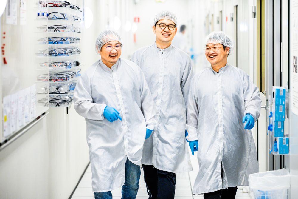 Deyu Tu, Dace Gao and Junpeng Ji, part of the research team developing artificial neurons, walking and smiling in protective clothing in the lab.