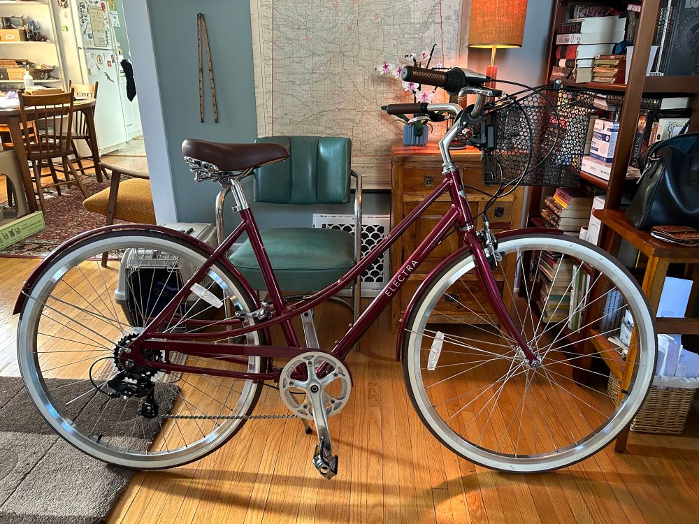 Sangria Electra Loft, brown seat and handles, whitewall tires, rainbow bell, black basket, had a couple scrapes from when it fell over but otherwise like new.
