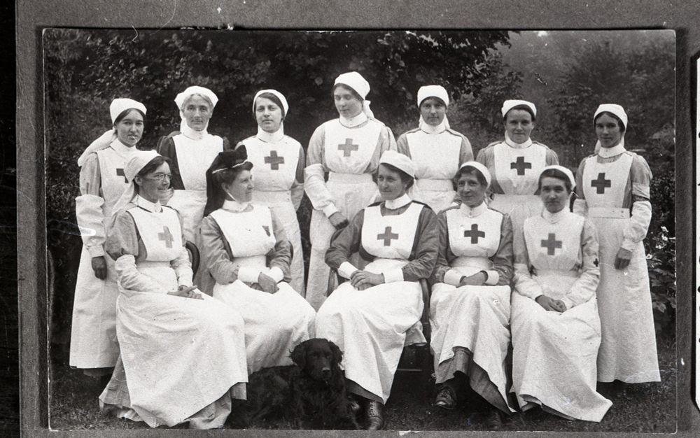 A group of nurses from Whittlesford Auxillliary Hospital in September 1916. They're all wearing uniforms, mostly with a big red cross on their long white aprons. A range of white nurses hats are visible.