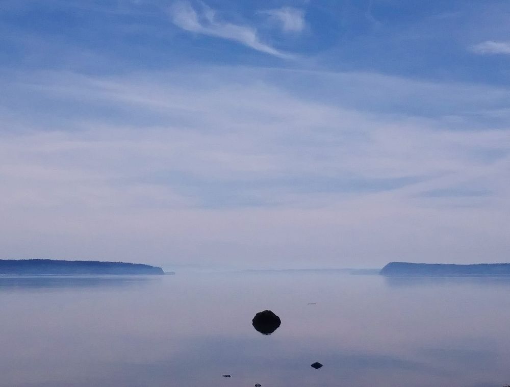 Puget Sound is almost a mirror, reflecting wispy clouds, islands, and dark rocks