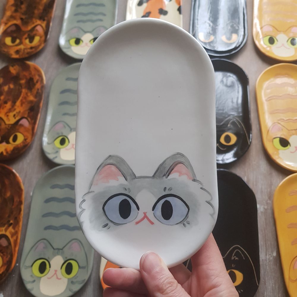 a ceramic tray I a shape of a white and grey cat, with more loaf shaped trays in the background