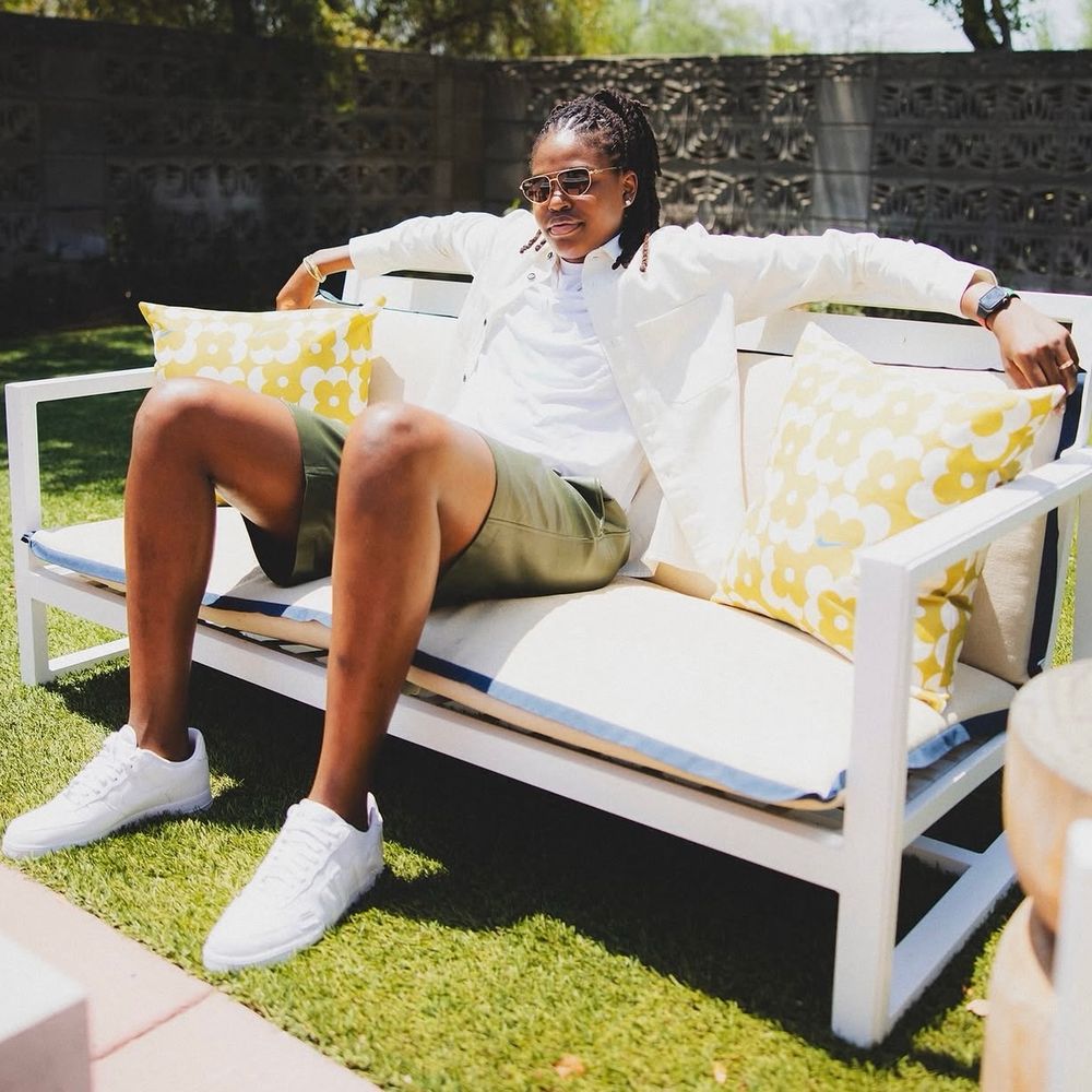 Jonquel Jones in shorts on a bench in the sun 