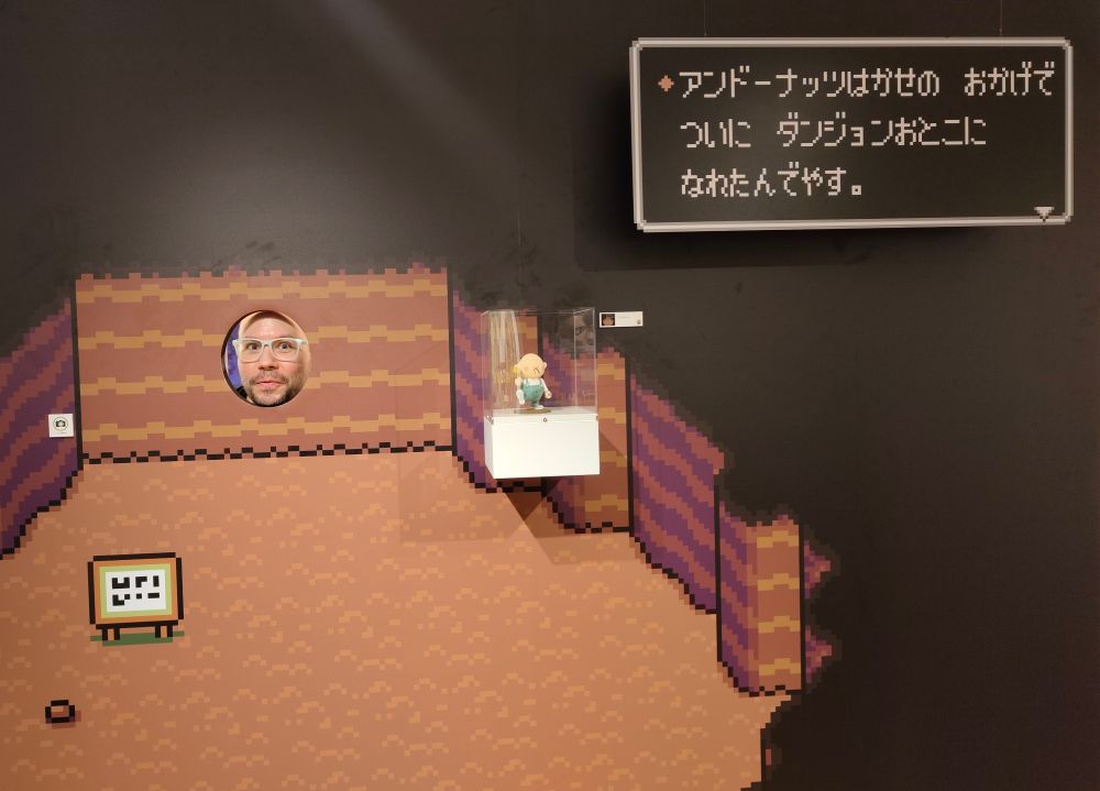 Dave at the Mother exhibit with their face in the Dungeon Man exhibit 