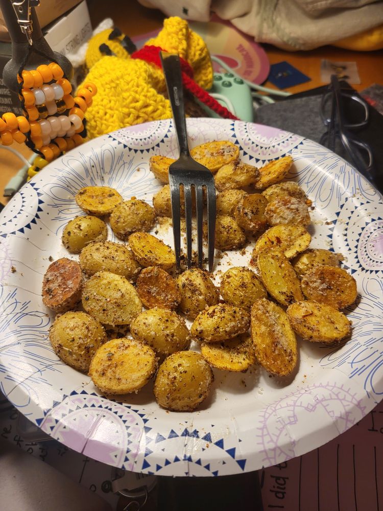 A paper plate with a pile of small halved golden potatoes.