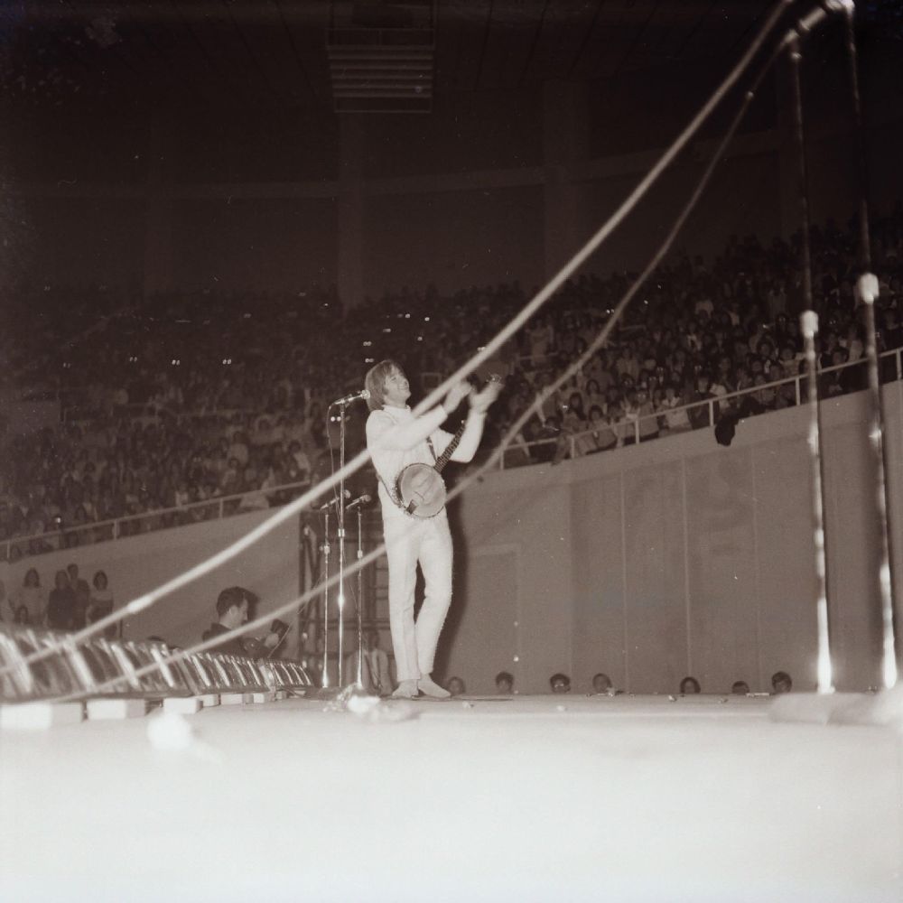 Peter Tork, dressed all in white and carrying his banjo, smiles at the concert audience in Phoenix, January 1967; photo by Richard Weize.