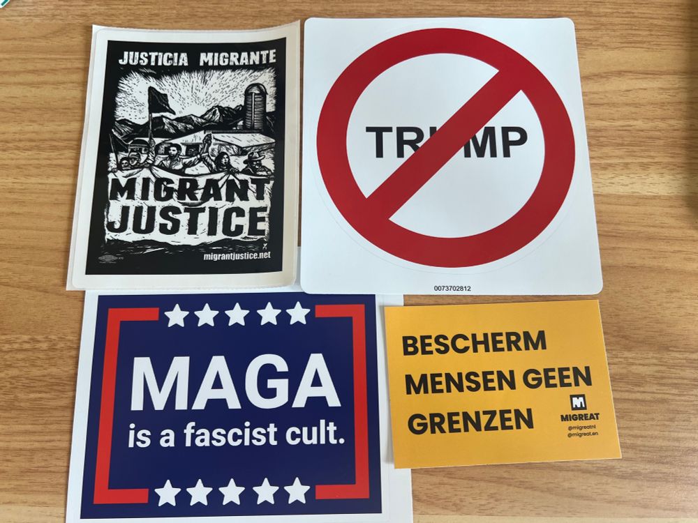 4 large stickers. One say Migrant Justice. One says MAGA is a facist cult. One says protect people, not borders (in Dutch) and one says ban Trump. 