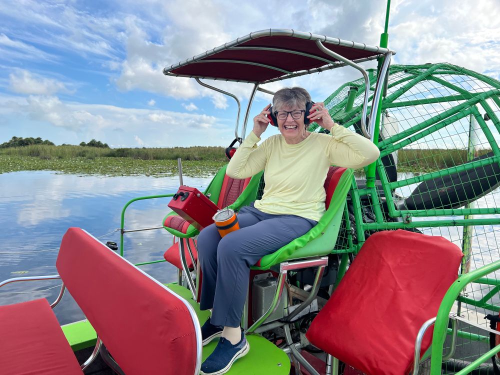 Woman wearing headphones smiling and sitting on an airboat 