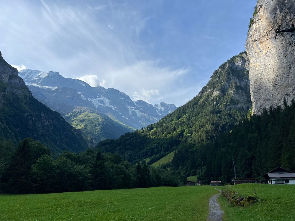 Trail towards a rock face and snowy mountains in the distance 