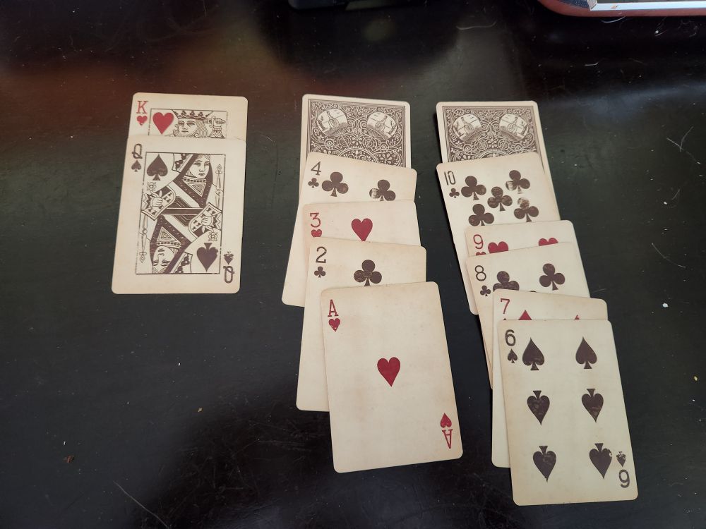 Photo of failed solitaire spread with only 2 cards face down. Those 2 cards are critical to finishing the game. 