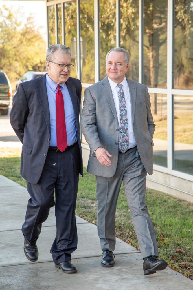 SwRI COO and Executive Vice President Walt Downing and President and CEO Adam L. Hamilton, P.E. stroll on the SwRI campus on a sunny day. 