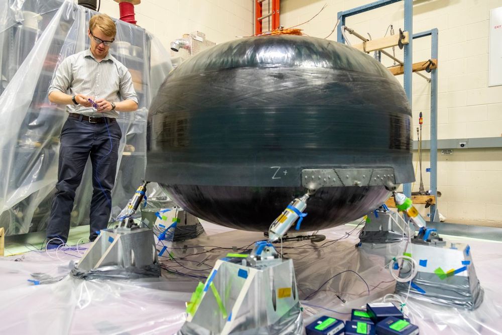 An engineer stands near a composite tank filled with cryogenic propellant. Testing is performed to ensure that the tanks can store and transport fuel safety under conditions associated with lunar missions.