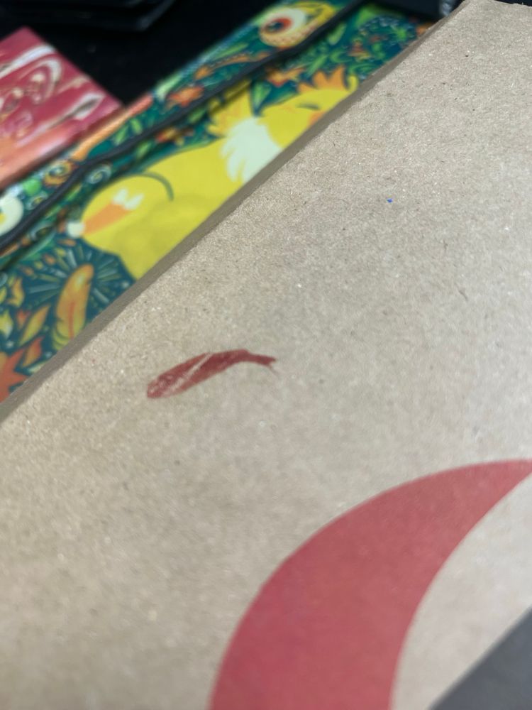 Close up image of the top of a Pizza Hut box. A smeared and dried up bit of blood is in the top of the box.