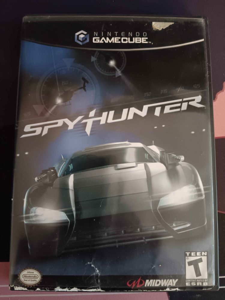 The case for Spyhunter on Gamecube sitting on my desk. It's dark and it shows a futuristic looking car racing towards the viewer as helicopters with spotlights fly overhead. Rated T for Teen and developed/published by Midway.
