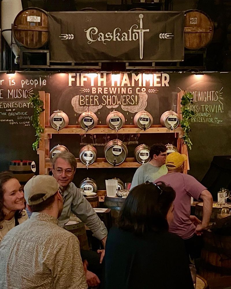 Cask pins (and a firkin) behind a group of people at a brewery taproom.