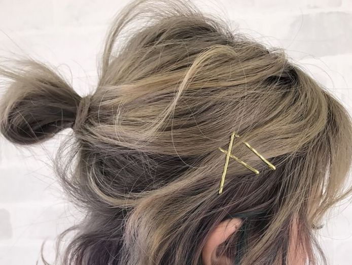 close-up on loose-bun, dirty-blonde hair with some hair clips in it. Face is obscured and aimed away from view.