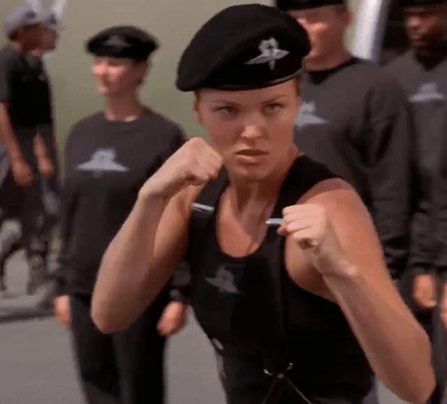 a woman wearing a black beret is standing in front of a group of soldiers