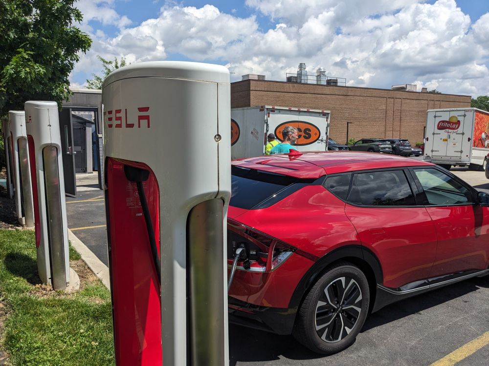 Red Kia car at a Tesla charging station 