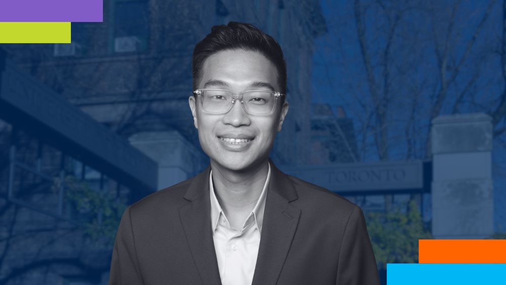 Professional headshot of an individual wearing a maroon blazer and light blue shirt, smiling confidently against a neutral dark grey background. 