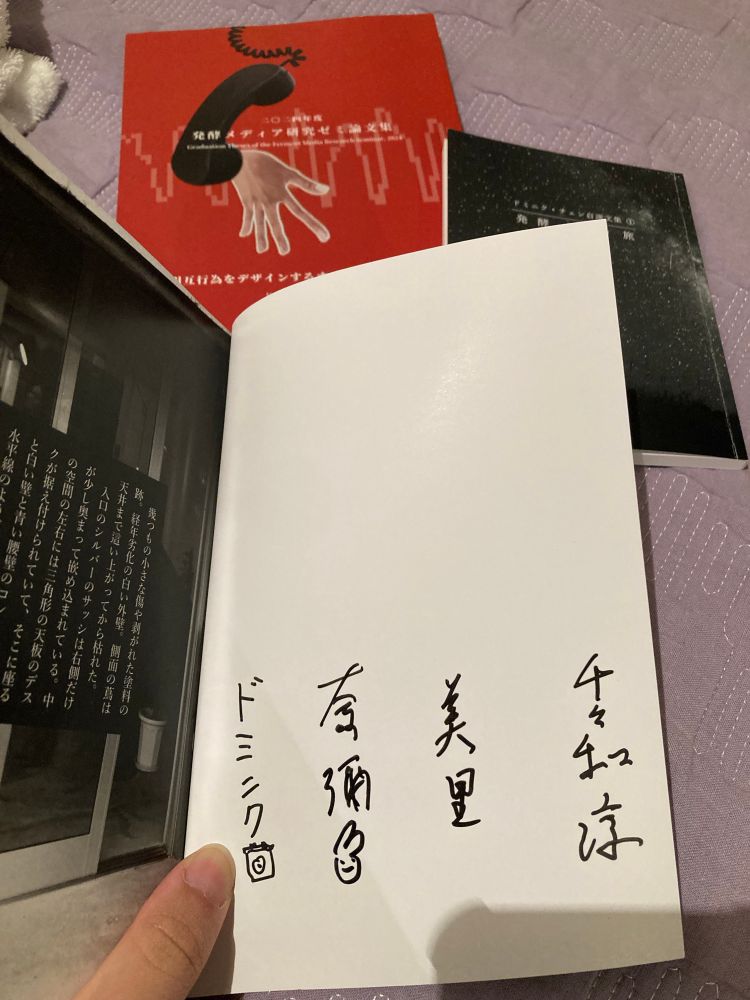 それぞれを並べた写真。表紙をめくったところに縦書きで4名のシンプルなサインが並ぶ。