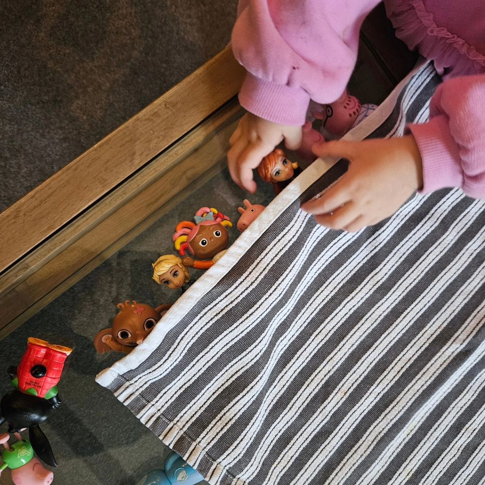 My friends 2.5hr old child using my tea towel that she pinched from the cooker, to make a bed for her toys.