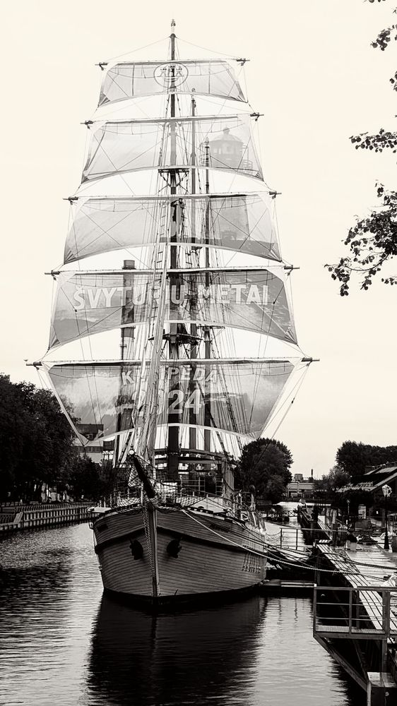 Ein Segelschiff mit drei Masten und voller Takelage in einem Kanal